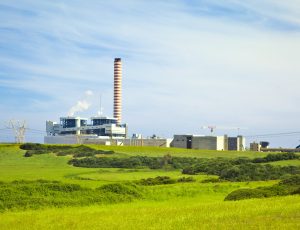 Factory with tall chimney in a green landscape